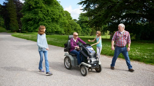 Visitor in a wheelchair on a walk with children in the garden at Tyntesfield, Somerset